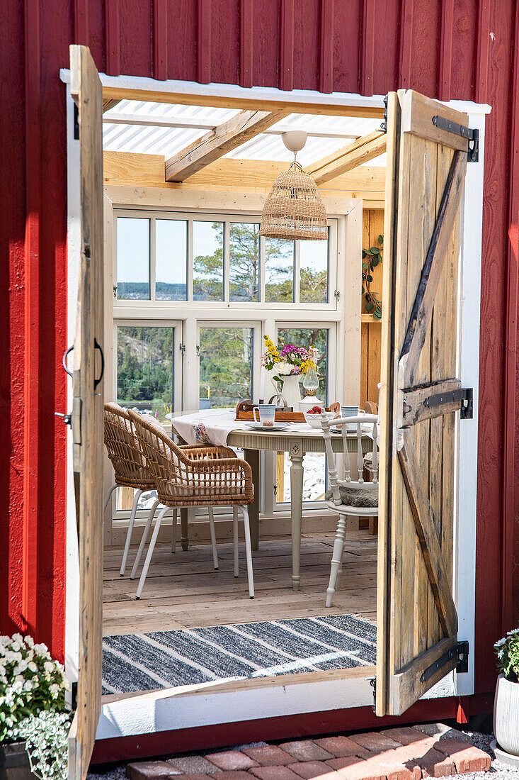 Blick in Gartenhaus mit gestreiftem Teppich und rundem Tisch mit Blumenstrauß