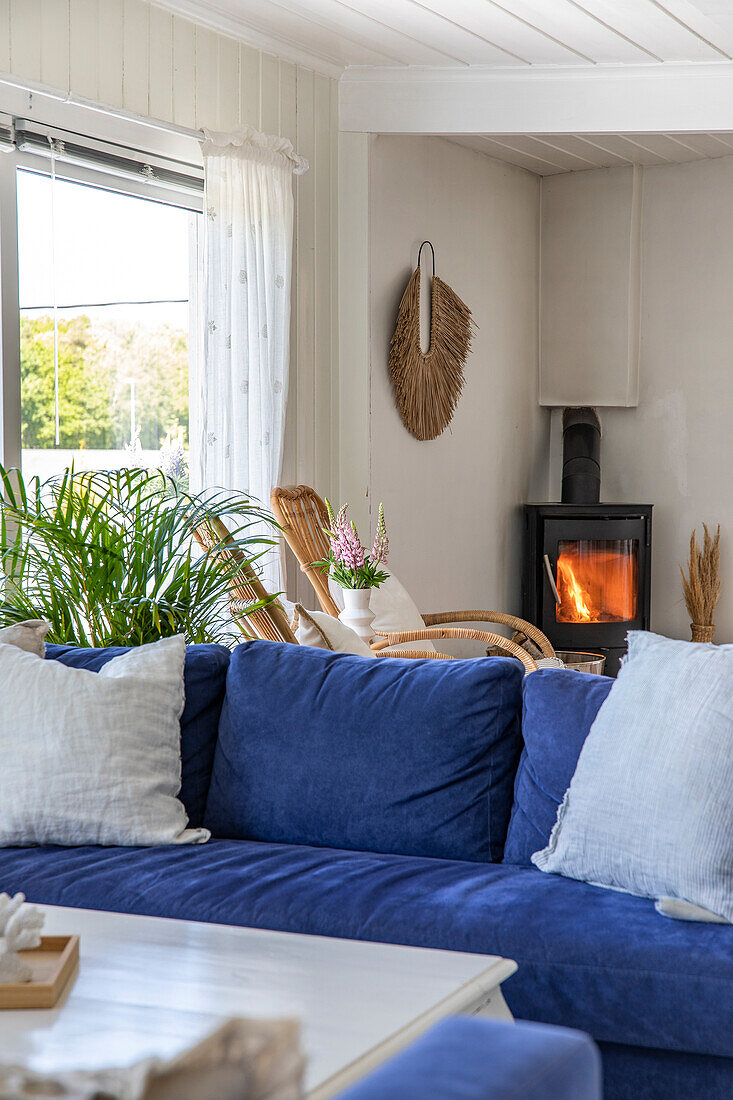 Blue sofa and rattan furniture in the living room with fireplace