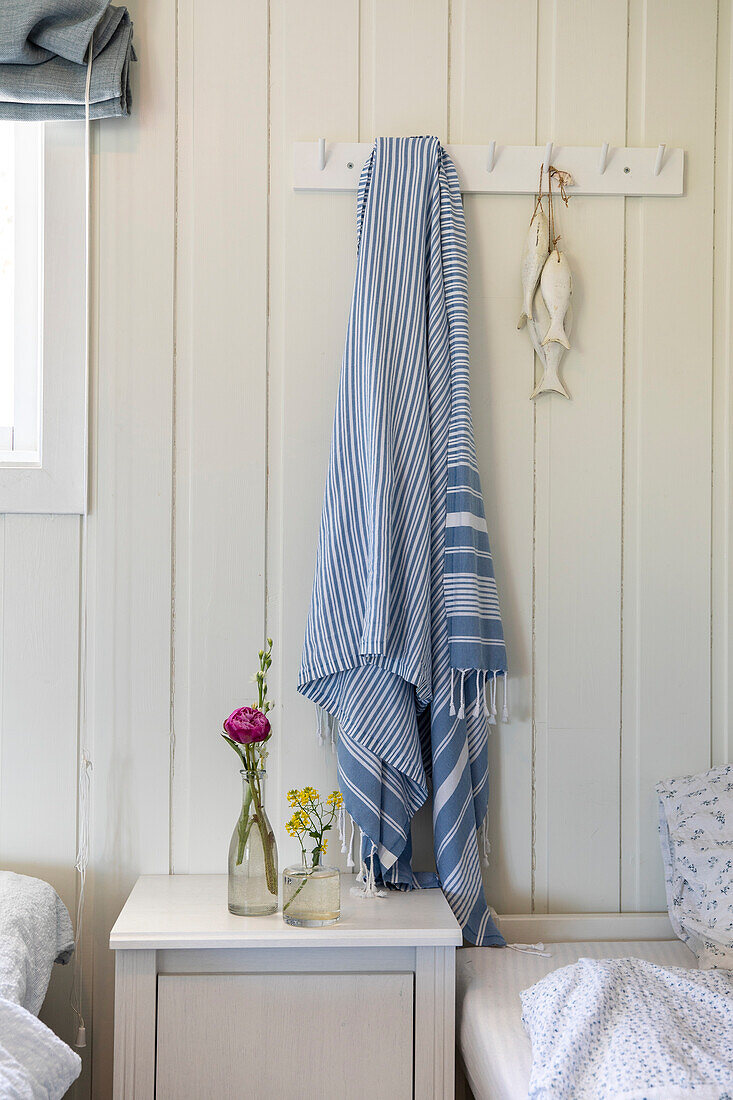 White bedroom with wooden paneling, hook rail and blue and white blanket