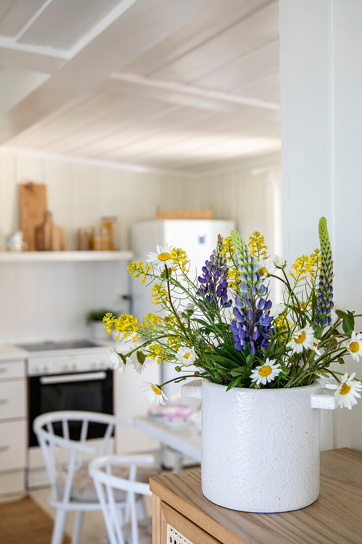 Bouquet of lupins and daisies in the kitchen with white wood paneling