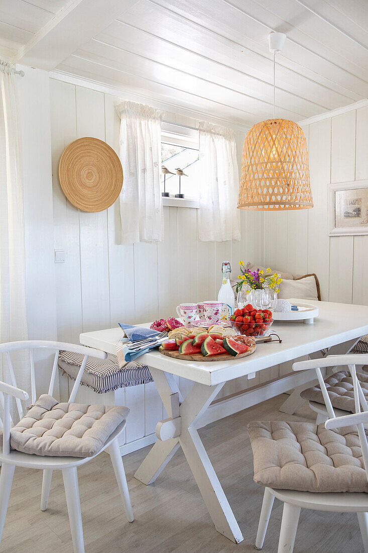 Set dining table with watermelon, strawberries and bouquet of flowers, Scandinavian style