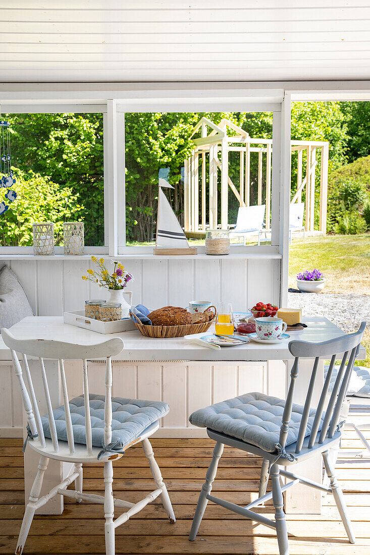 Frühstückstisch mit Gebäck und Tee auf Veranda mit Gartenblick