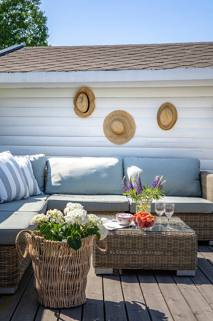 Garden lounge with wicker furniture, decorated with hydrangeas and lupins