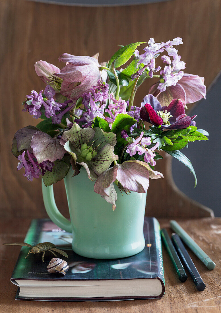 Blumenstrauß aus Lenzrosen (Helleborus) und Frühlingsblumen in grünem Becher