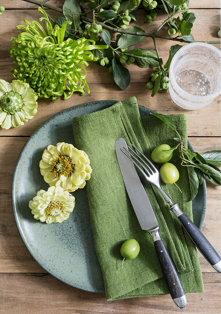 Green, natural table centrepiece with flowers and branches on a wooden background