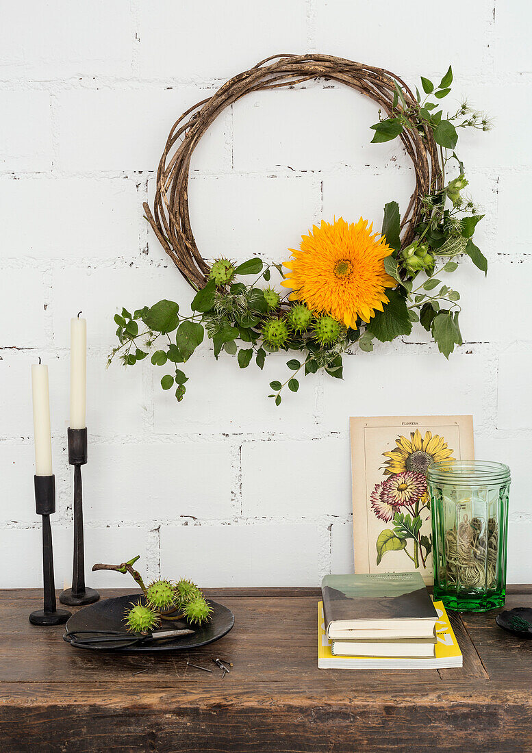 Decorative wreath of twigs and orange-coloured blossom on white brick wall