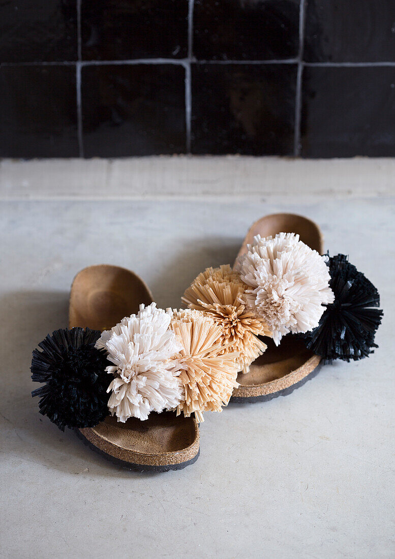 Summer shoes with decorative fabric tassels on concrete floor