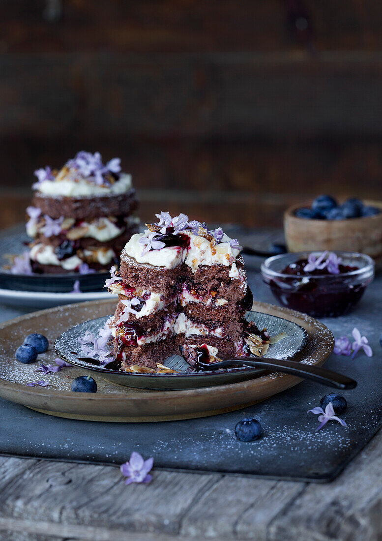 Schokoladentörtchen mit Beeren und Blüten auf rustikalem Holztisch