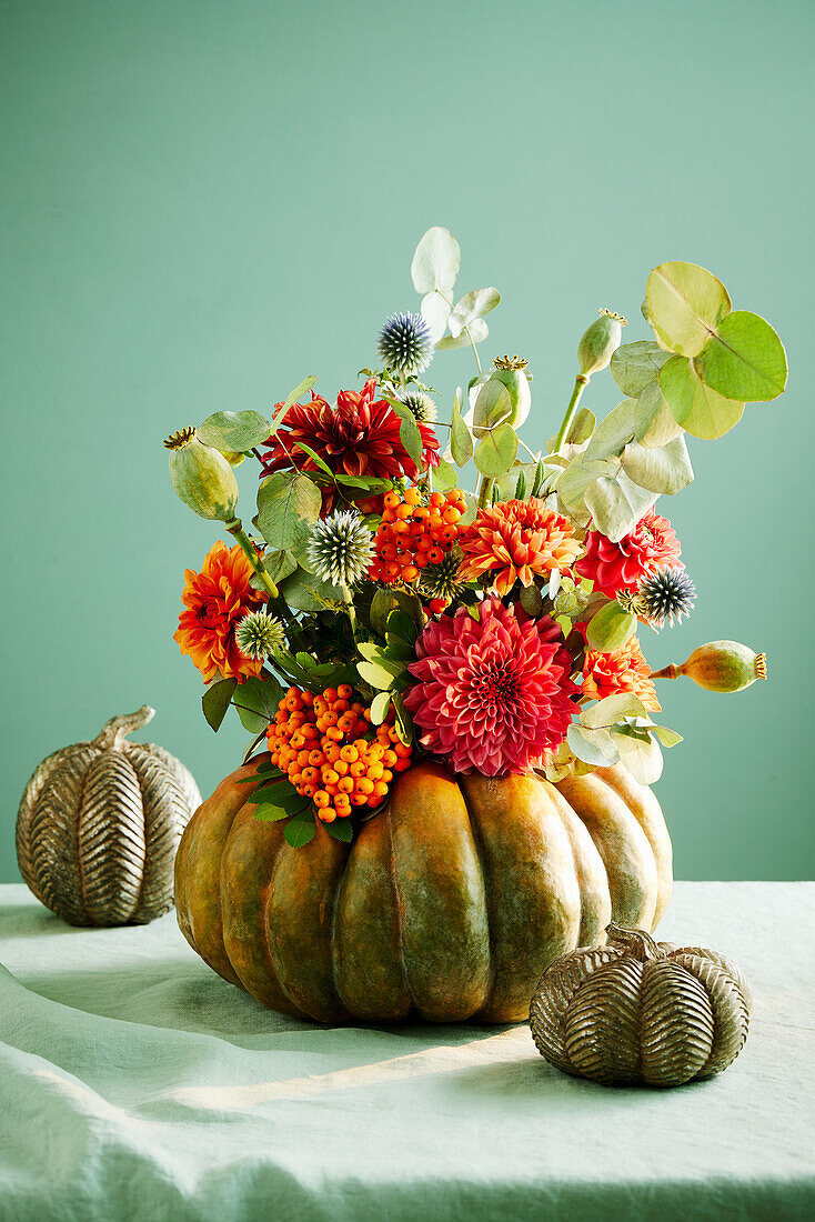 Pumpkin vase with winter flowers - dahlias, thistles, rowan branches