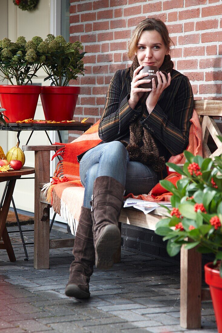 Frau trinkt Kaffee auf einer Herbstterrasse