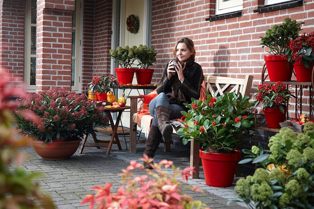 Frau trinkt Kaffee auf einer Herbstterrasse