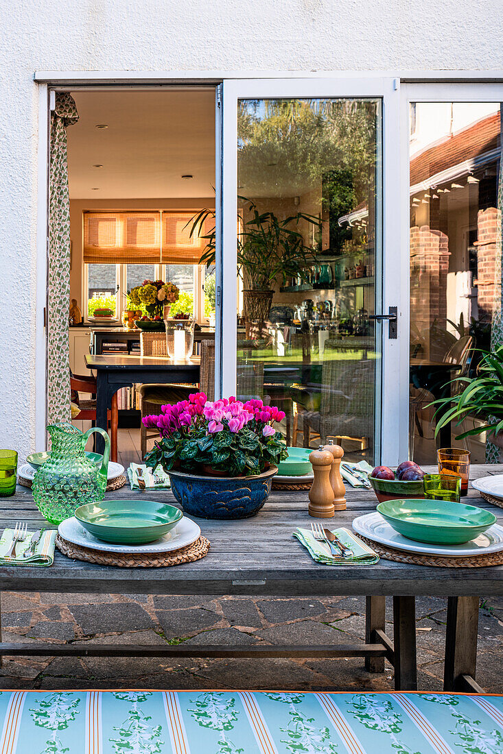 Laid garden table with flower arrangement and view into the kitchen