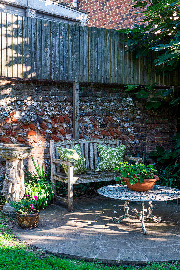 Small garden area with wooden bench, stone table and ornamental plants