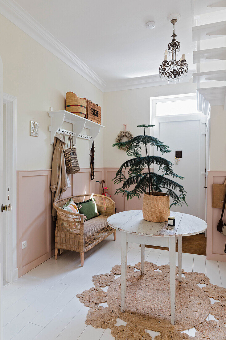 Entrance area with rattan sofa, small round table and araucaria plant