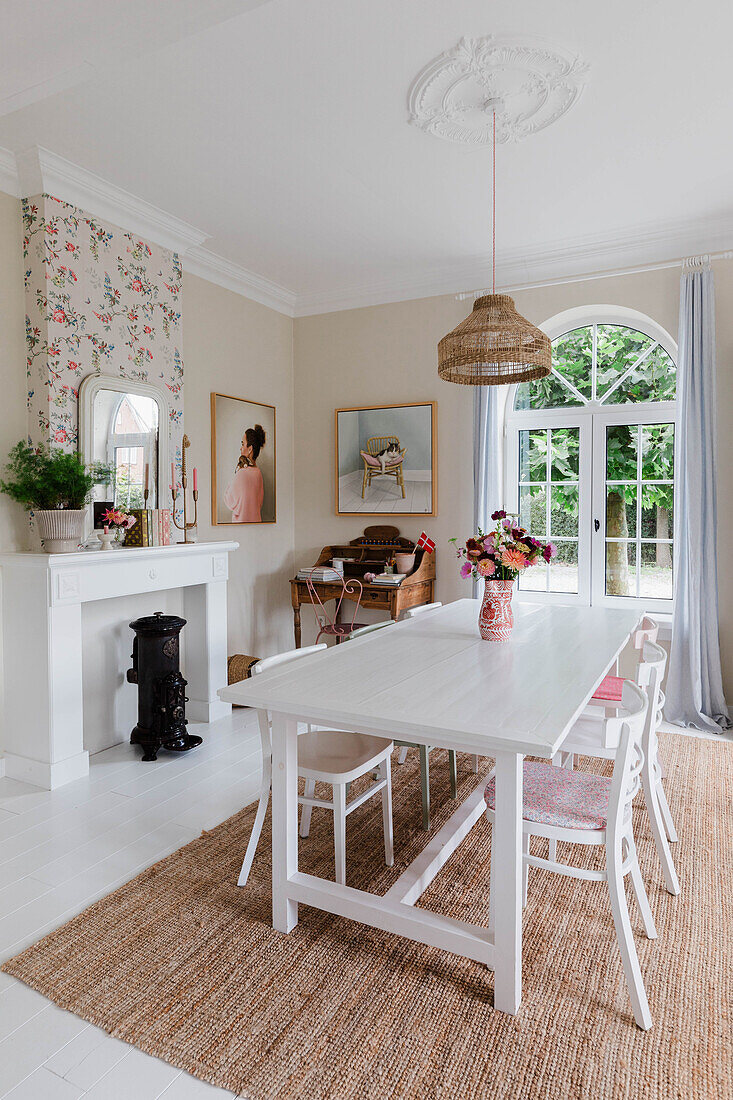 Dining room with white dining table and chairs, wood-burning stove and floral wallpaper