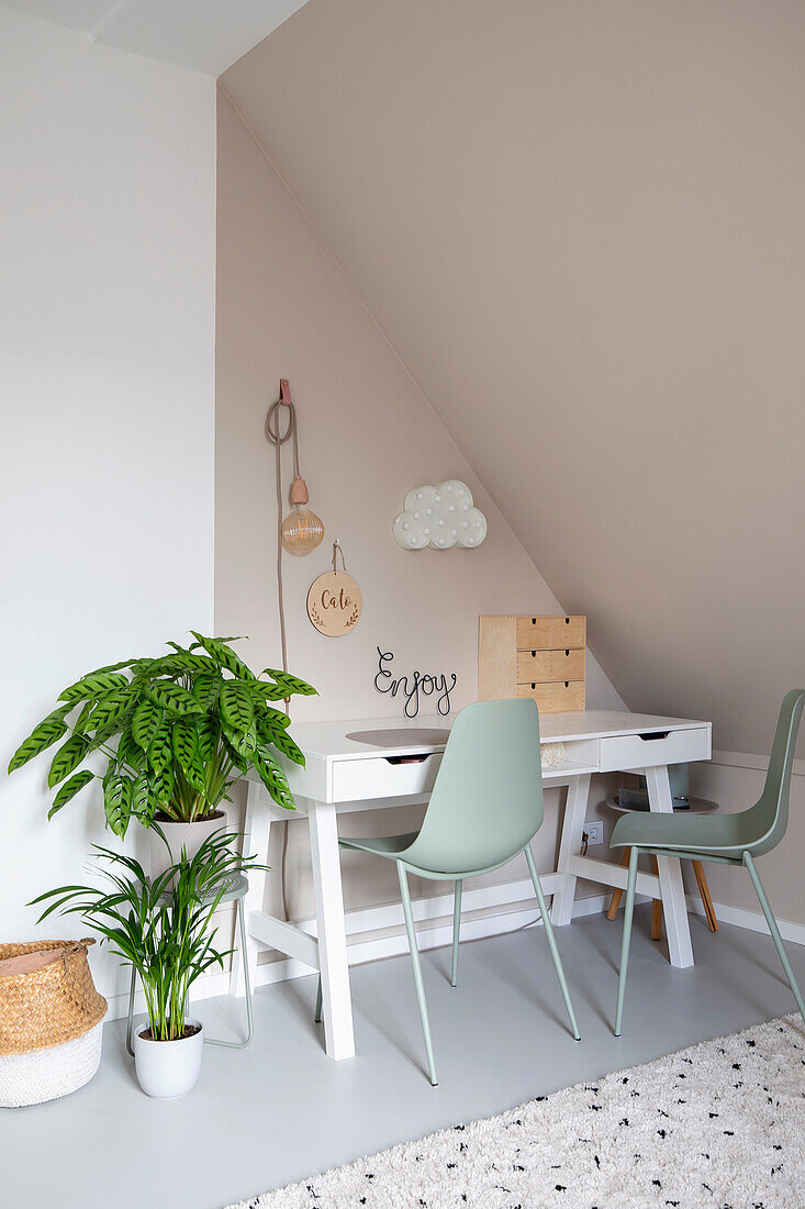 Bright workplace with white desk and mint green chairs under a sloping roof