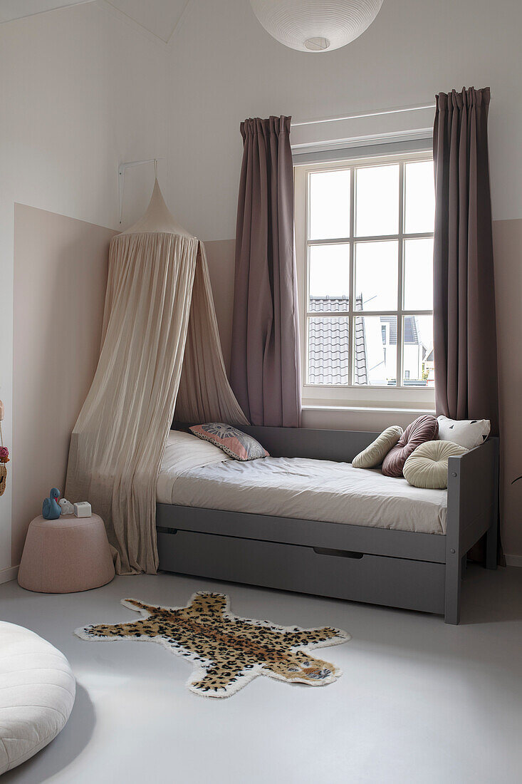 Children's room with grey bed and canopy and leopard carpet