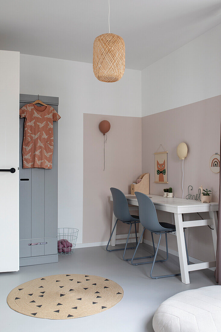 Children's room with desk, grey chairs, pink walls and hanging rattan basket lampshade