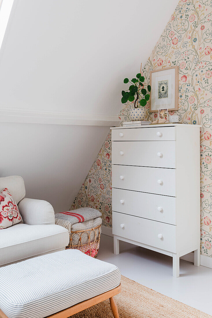 White drawer unit in attic bedroom with floral pattern wallpaper