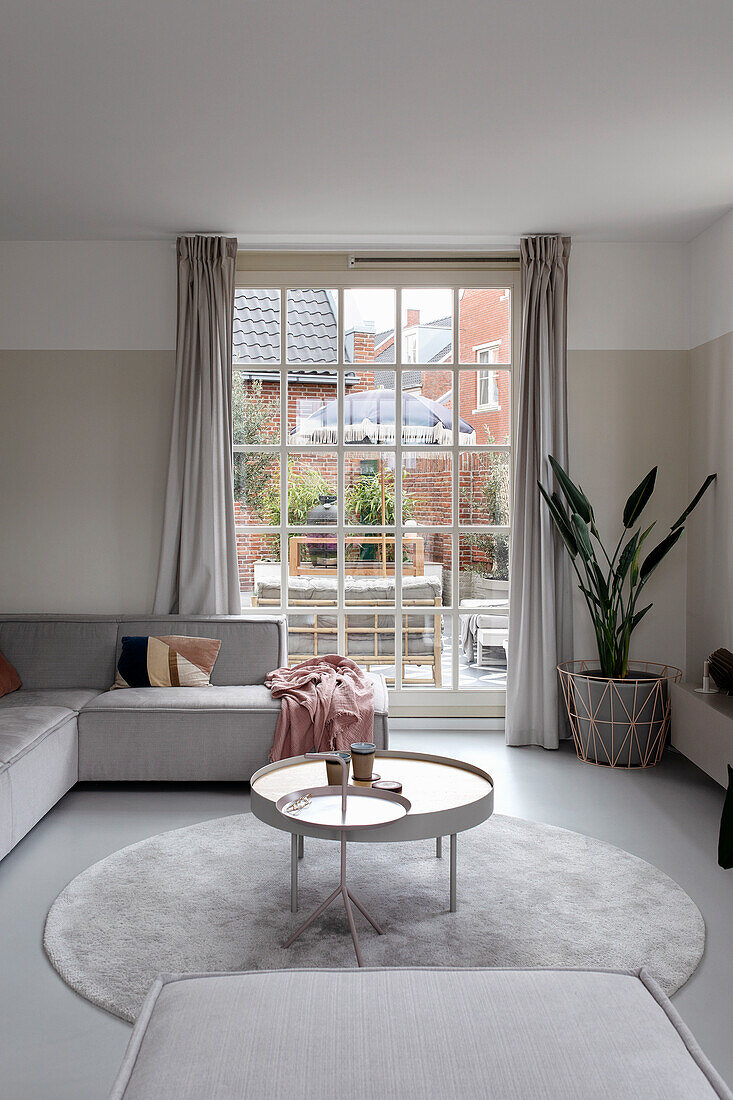 Modern living room with grey sofa and large window to the terrace