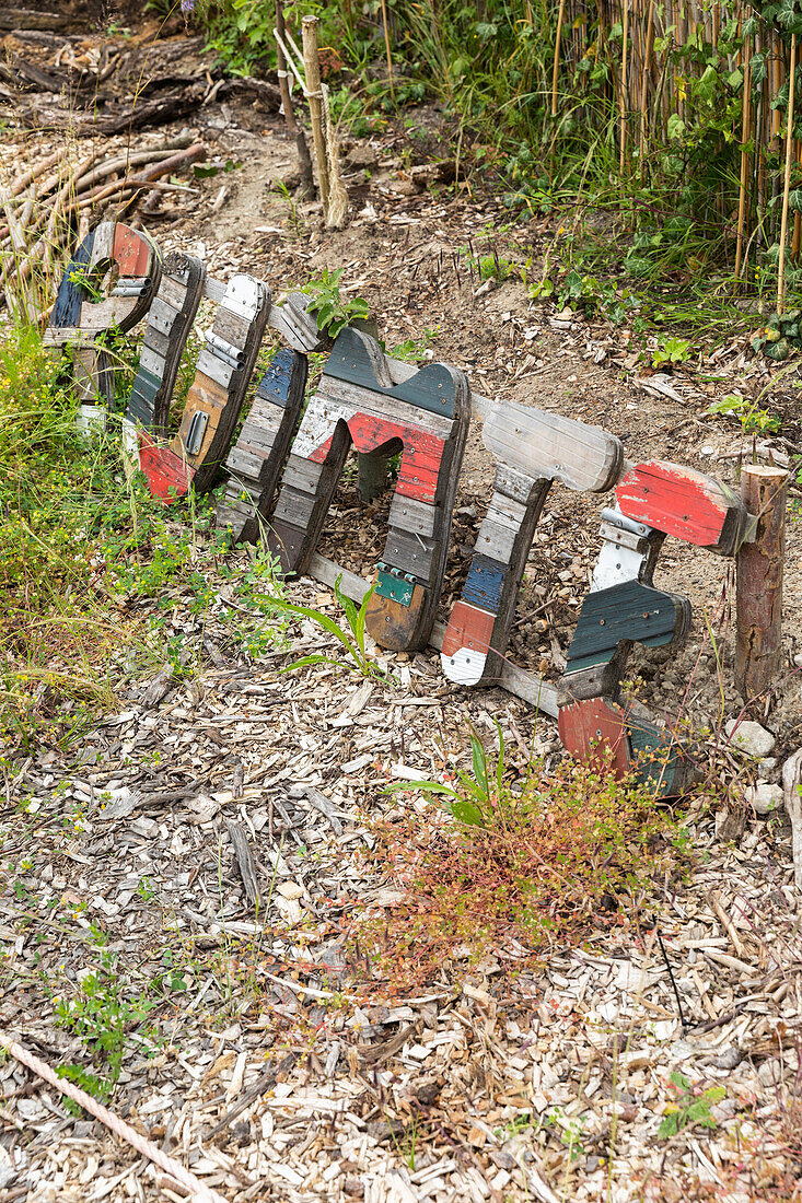 Bunt bemaltes Holzschild in einem Naturgarten