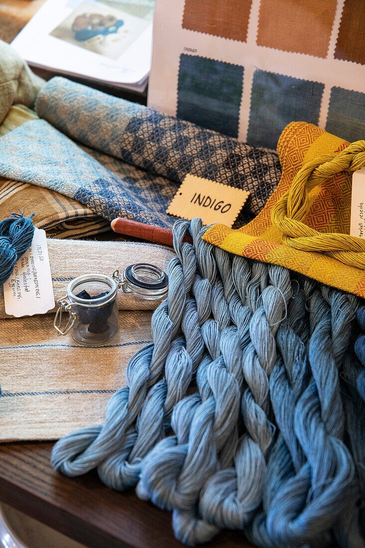 Fabrics and yarn in different shades of blue with colour samples on table