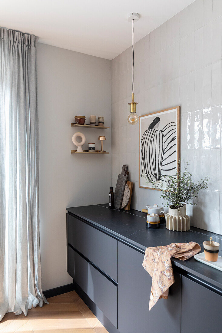 Modern kitchen with black fronts, minimalist shelving and artwork on tiled wall