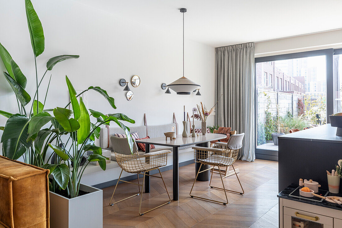 Dining area with golden metal chairs, pendant light and view of the terrace