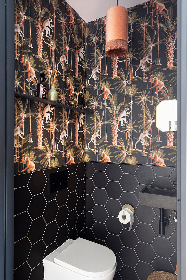 Stylish guest WC with black hexagon tiles and jungle wallpaper