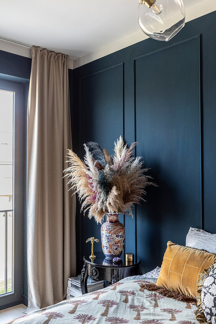 Bedroom with dark blue accent wall and dried flower arrangement in elegant vase