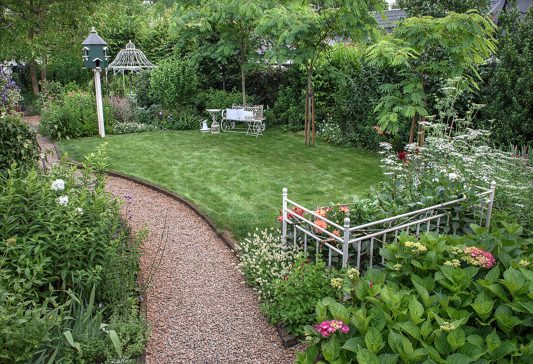 Green garden with manicured lawn, bench and metal gazebo