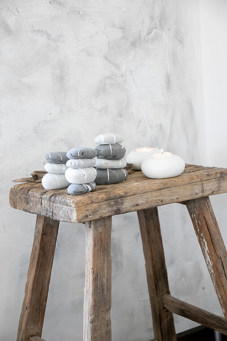 Decorative stacks of stones and candles on a rustic wooden stool