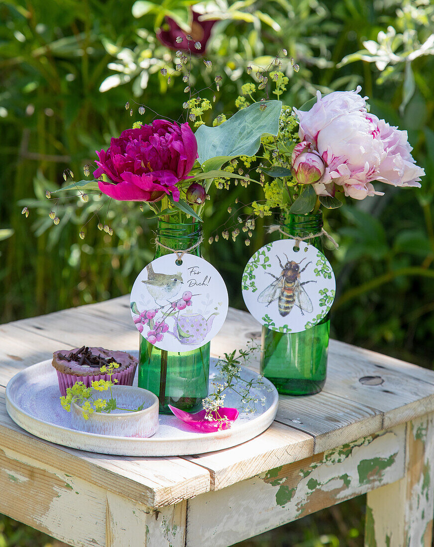 Peonies (Paeonia) in green bottles with round paper tags