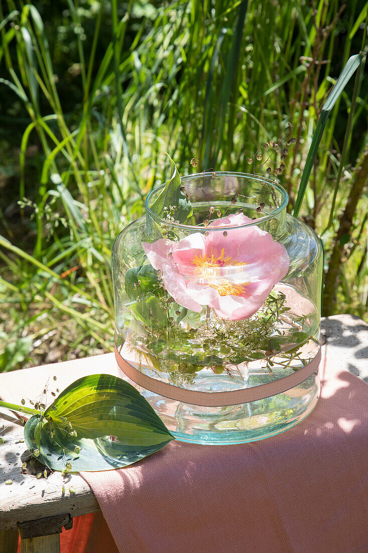 Rosenblüte in dekorativer Glasvase im Garten