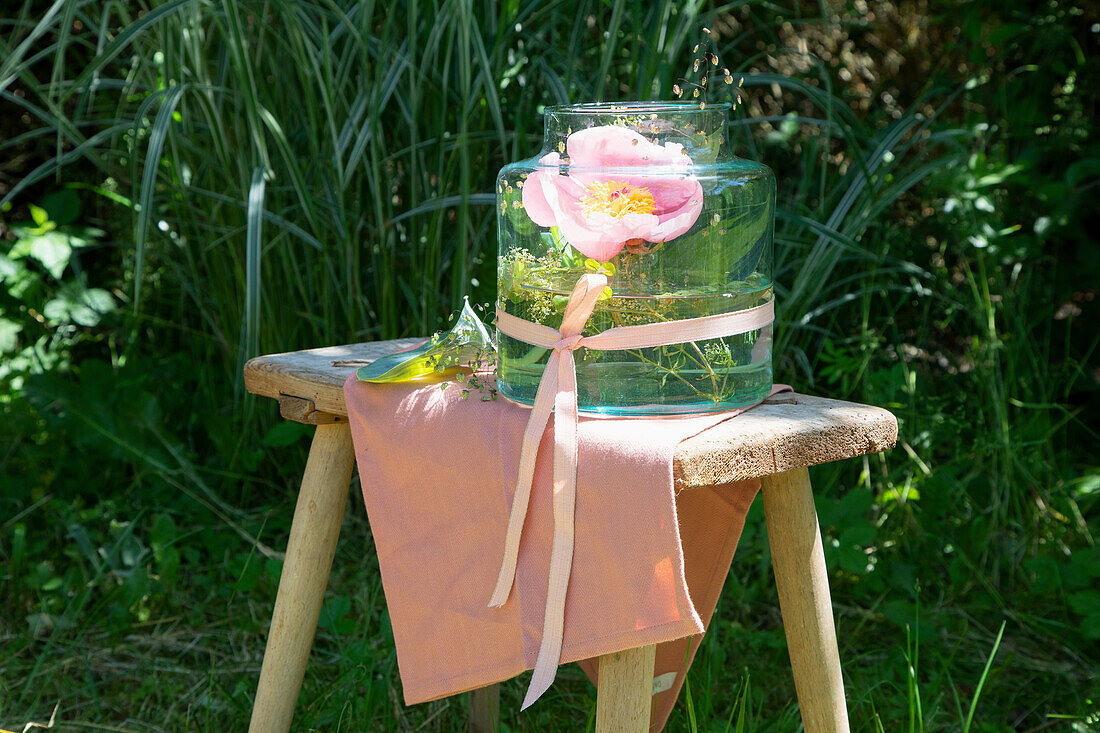 Large vase with decorative plant on wooden stool in the garden