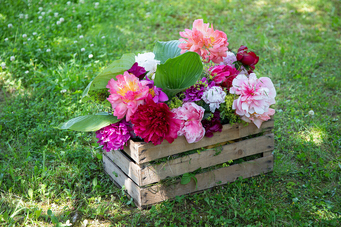 Colourful flower arrangement of peonies in a wooden box