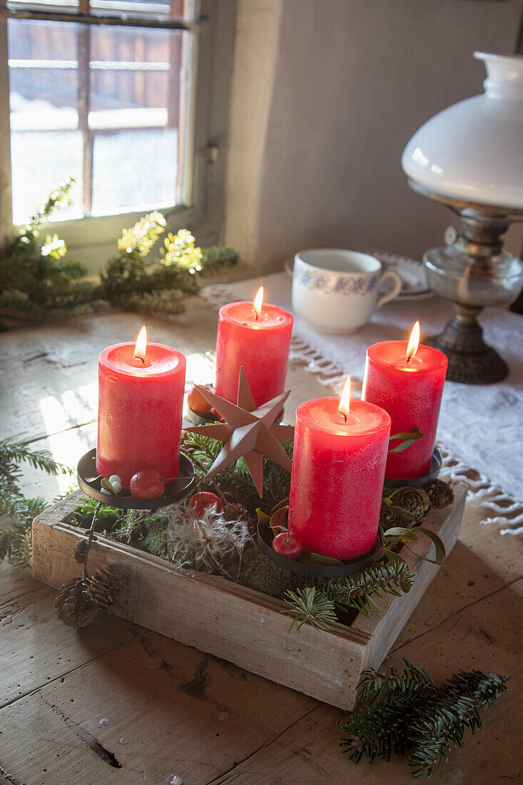 Advent wreath with four red candles and Christmas decorations on a wooden table