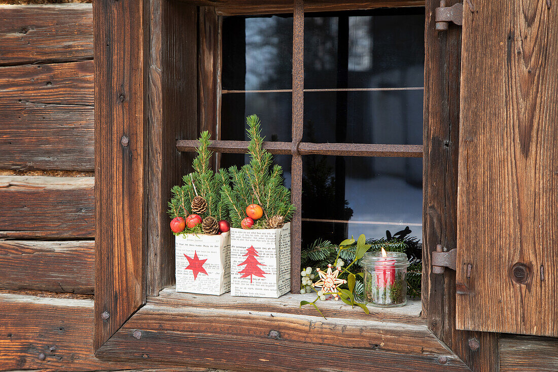 Weihnachtlich dekoriertes Fensterbrett mit Tannenbäumchen-Deko und Kerze