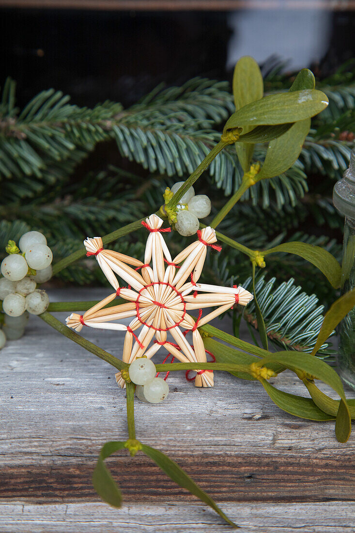 Straw star and mistletoe branches on a rustic wooden table