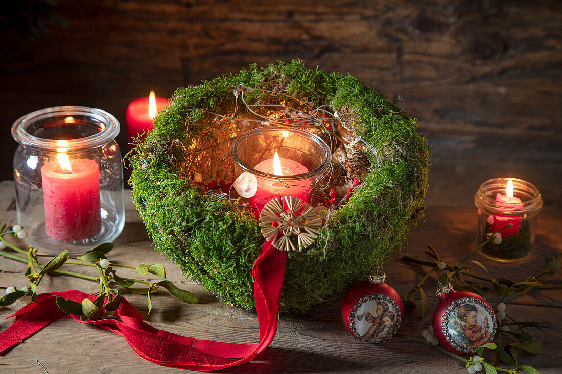 Weihnachtlich dekoriertes Moosgesteck mit Teelichtern und Christbaumkugeln