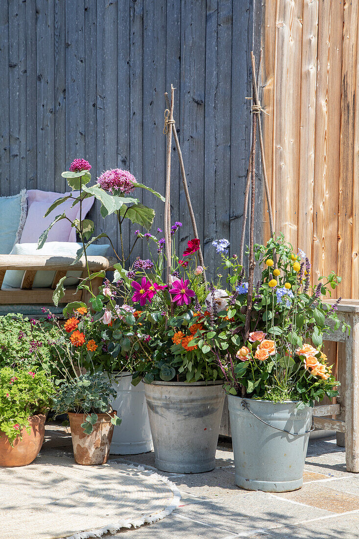 Flower arrangement in metal buckets on sunny terrace