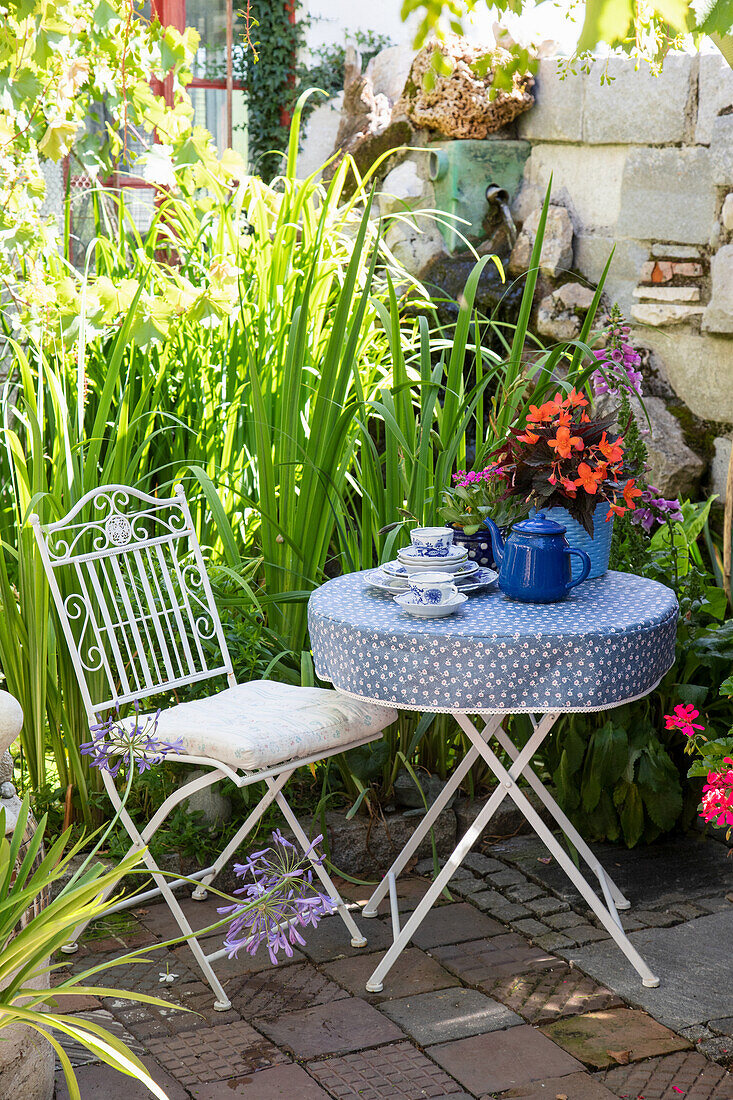 Metalltisch mit blauer Tischdecke und Teeservice im Garten