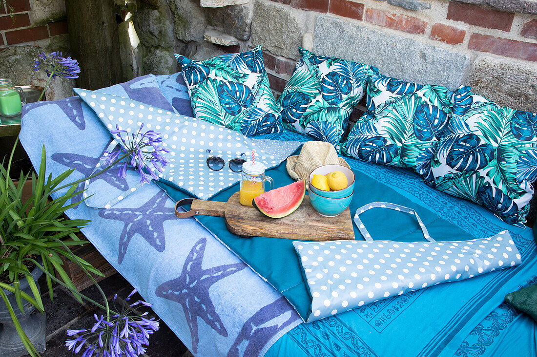 Outdoor lounge with patterned cushions and wooden board with fresh fruit