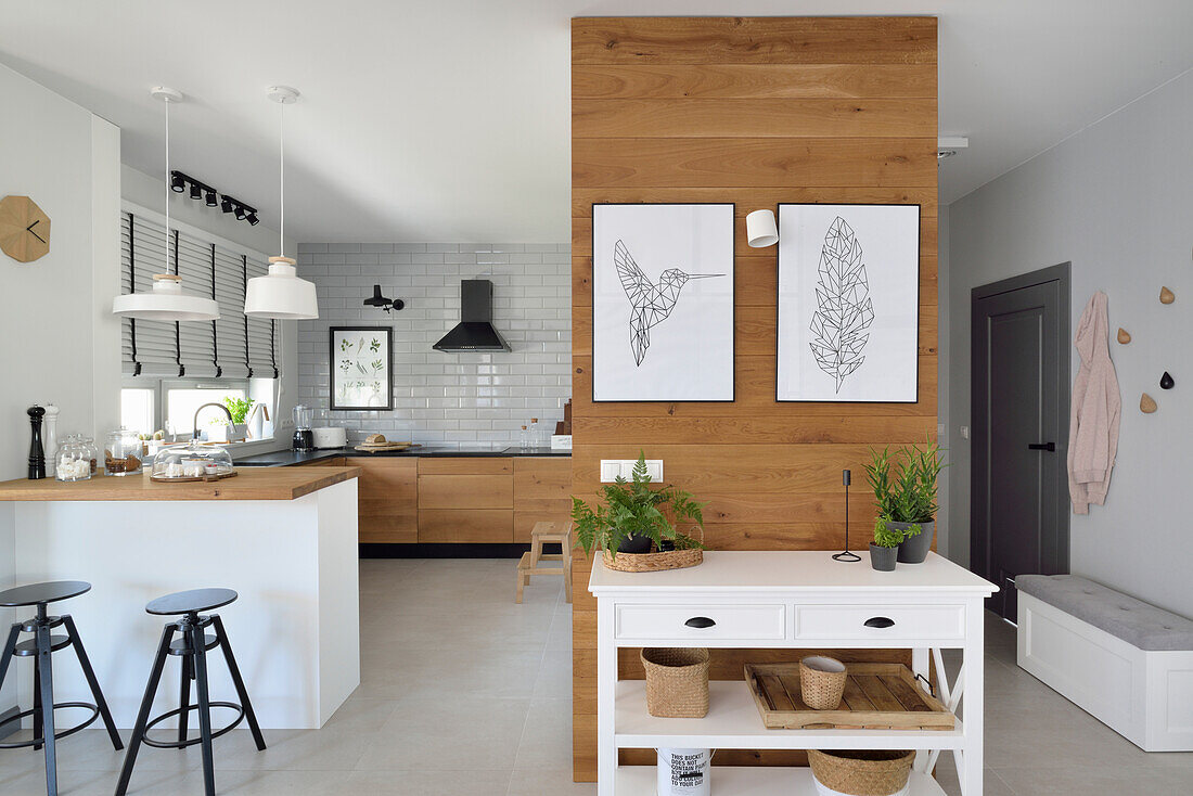 Modern gestaltete Küche in Holz und Weißtönen mit Insel und Sitzgelegenheiten