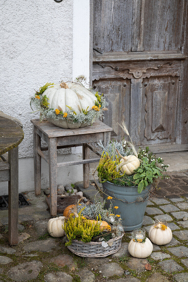 Herbstdekoration mit Kürbissen und Wildblumen vor rustikaler Holztür