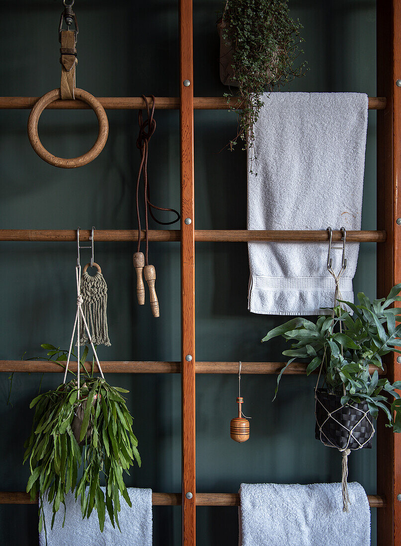 Kletterwand aus Holz mit Handtüchern und hängenden Pflanzen im Badezimmer