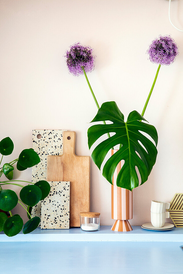 Monstera-Blatt und Zierlauch (Allium) in gestreifter Vase