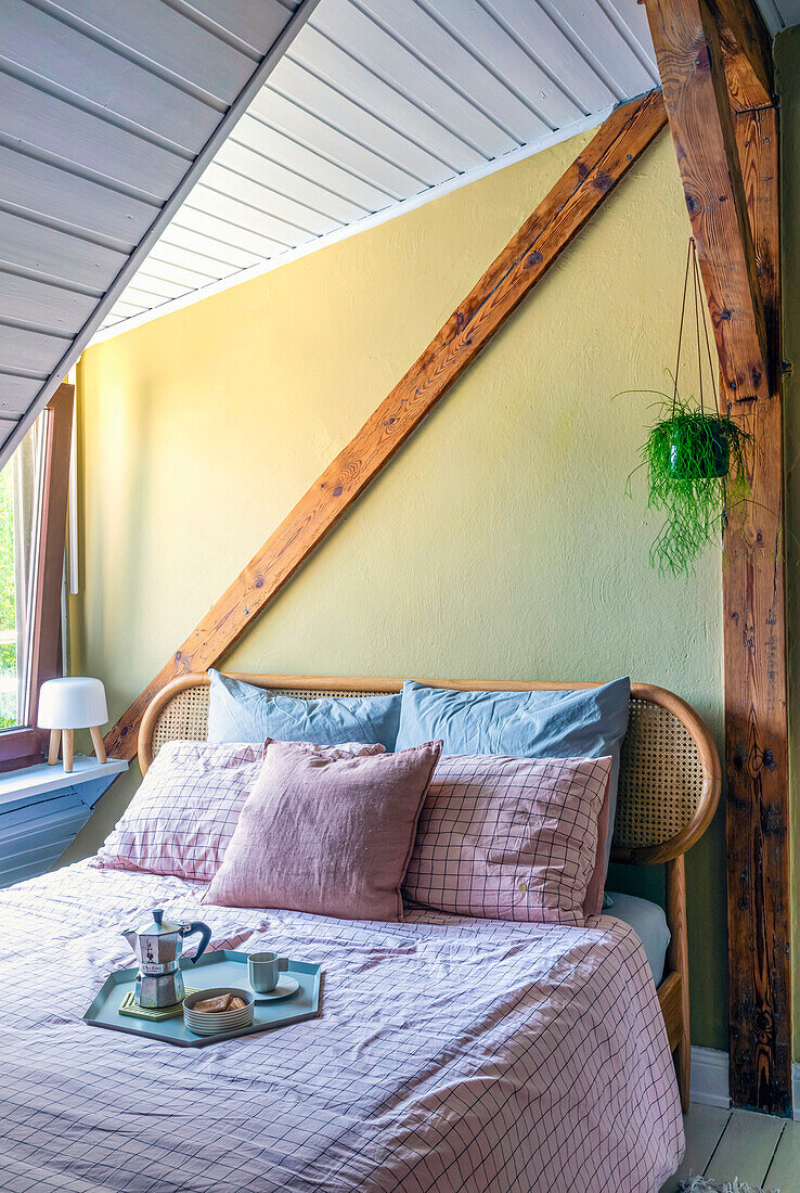 Attic room with wooden beams, double bed and breakfast tray