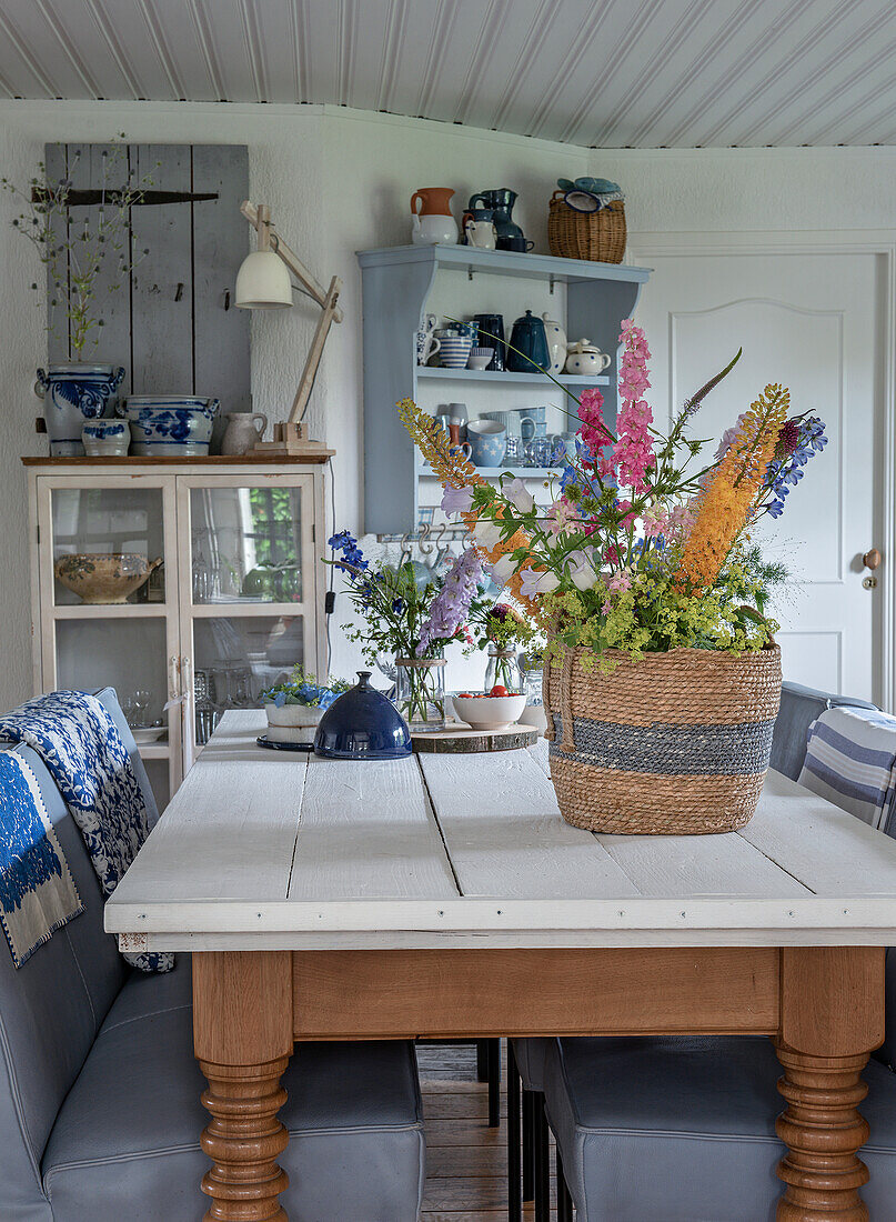 Country-style kitchen with basket full of flowers on wooden table