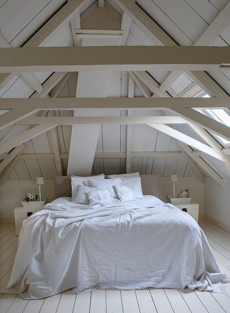 Schlafzimmer im Dachgeschoss mit weißen Holzbalken und Doppelbett